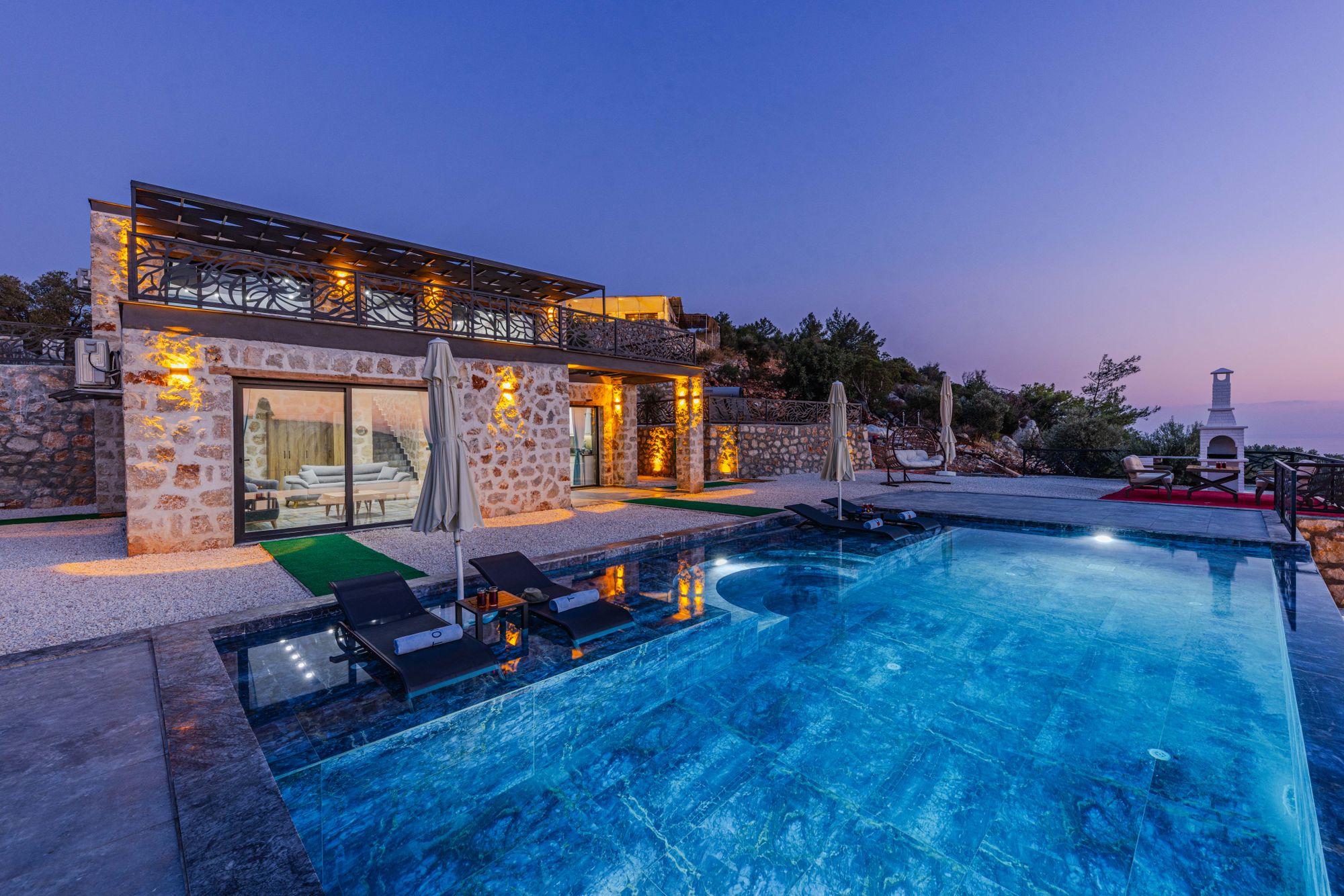 Beleuchtete Luxusvilla mit Infinity-Pool zur blauen Stunde