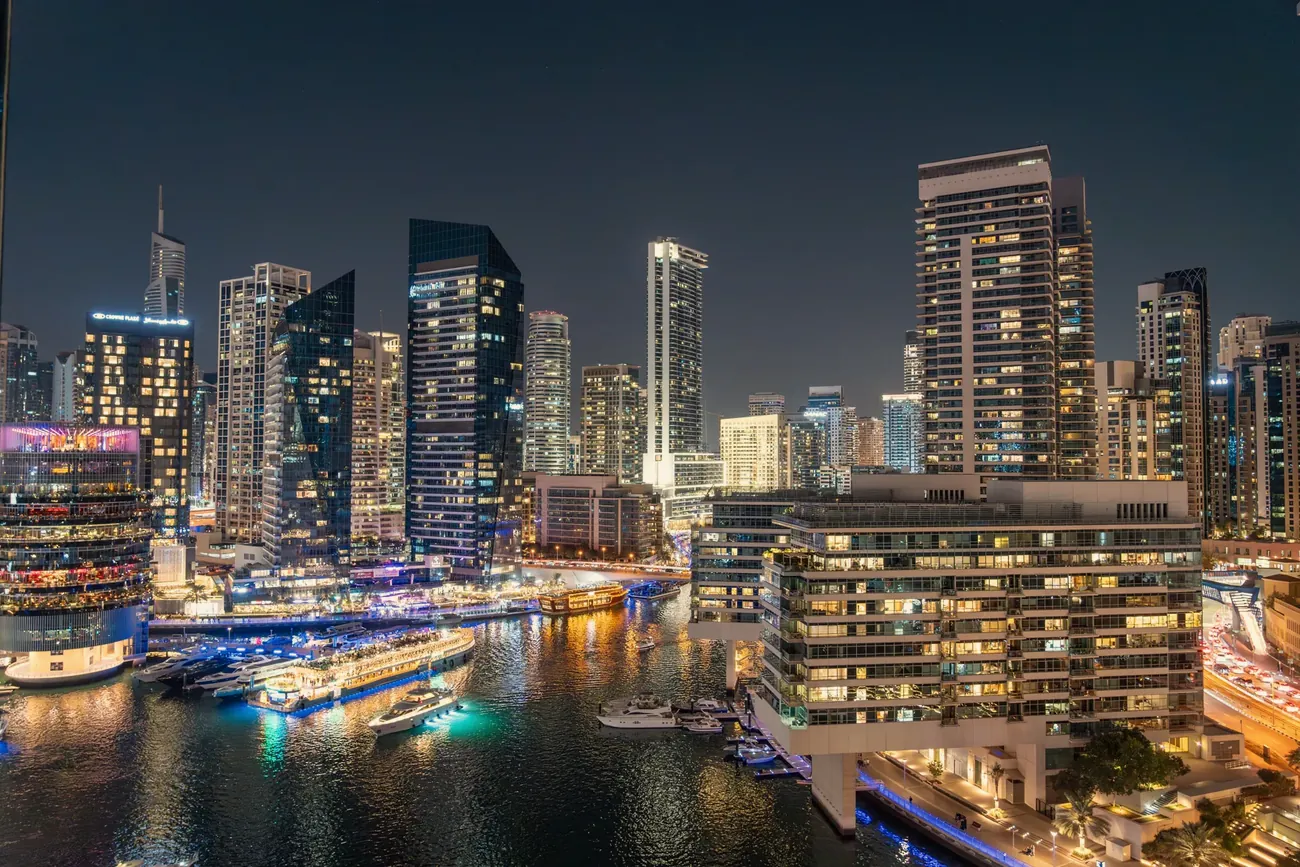 Beleuchtete Skyline der Dubai Marina bei Nacht am Wasser