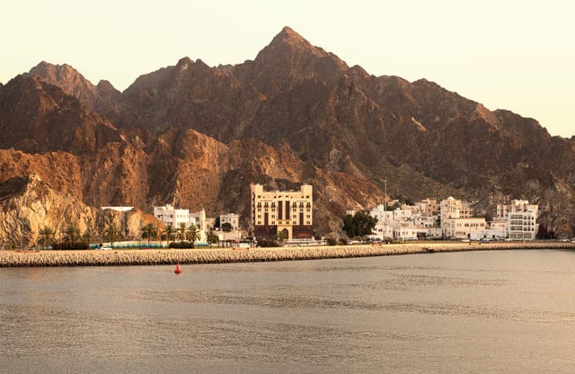 ساحل مسقط أمام الجبال في ضوء دافئ